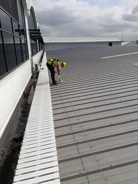Roofer inspecting an industrial roof gutter